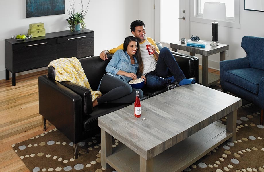 Man and woman on couch in living room with coffee table made from Seasoned Planked Elm Formica Laminate